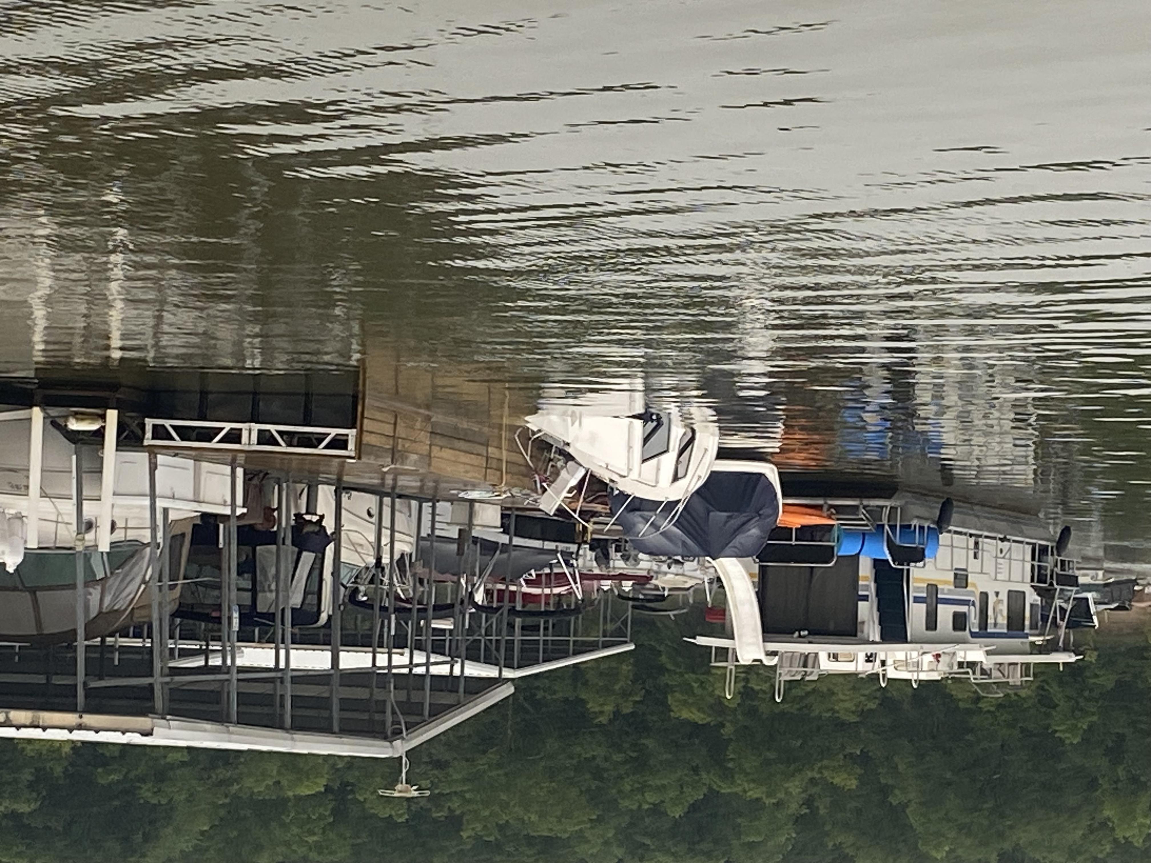 Rear end of boat sitting on lake bottom with the bow being held at surface by dock lines.