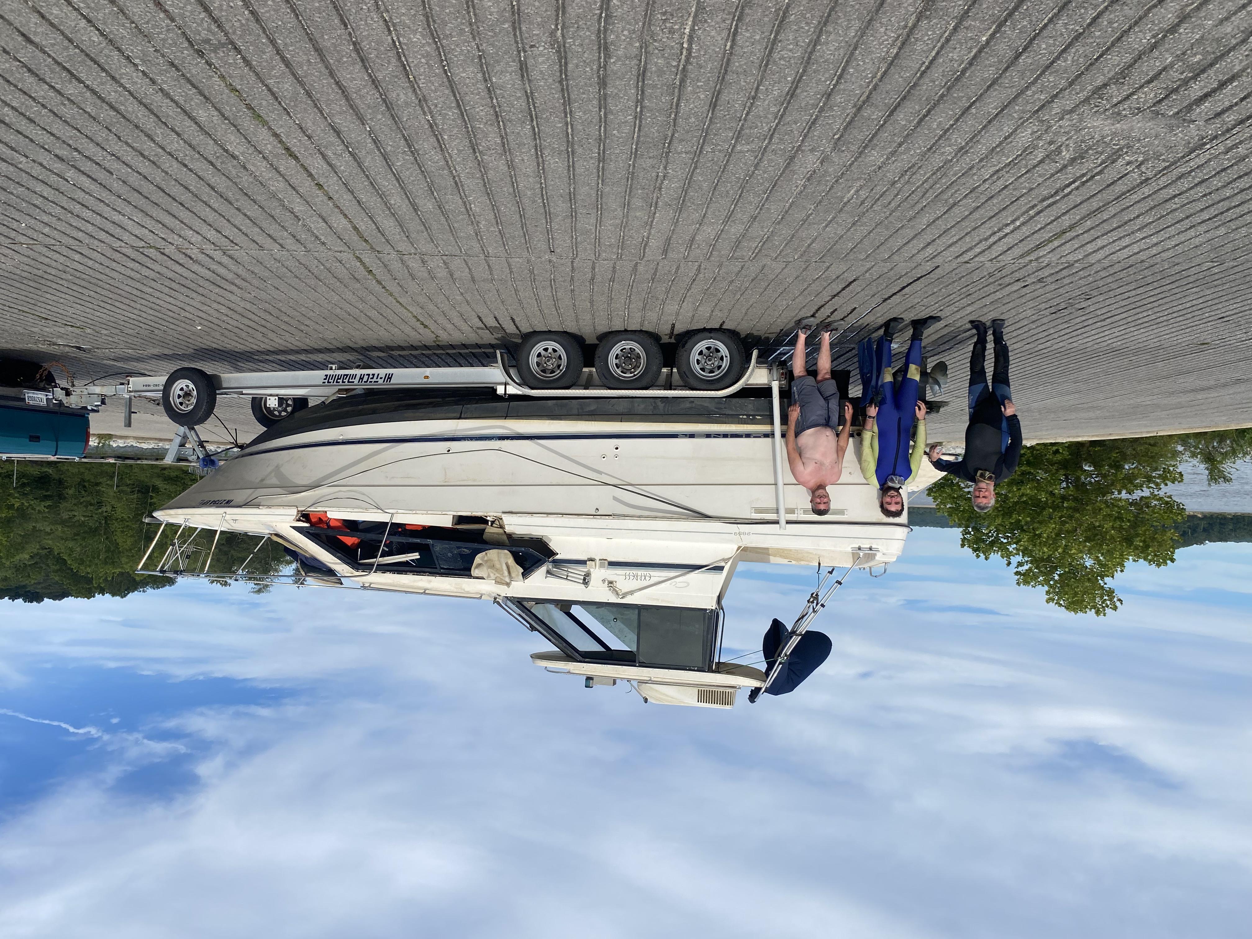 Boat on trailer after being removed from water with divers standing infront of the boat.